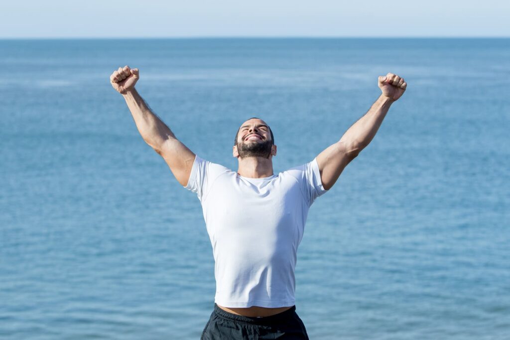 Man celebrating victory by the sea.