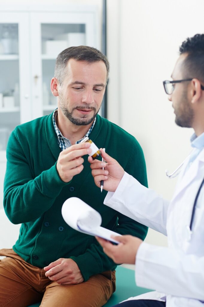 A man is holding something in his hand while talking to a doctor.