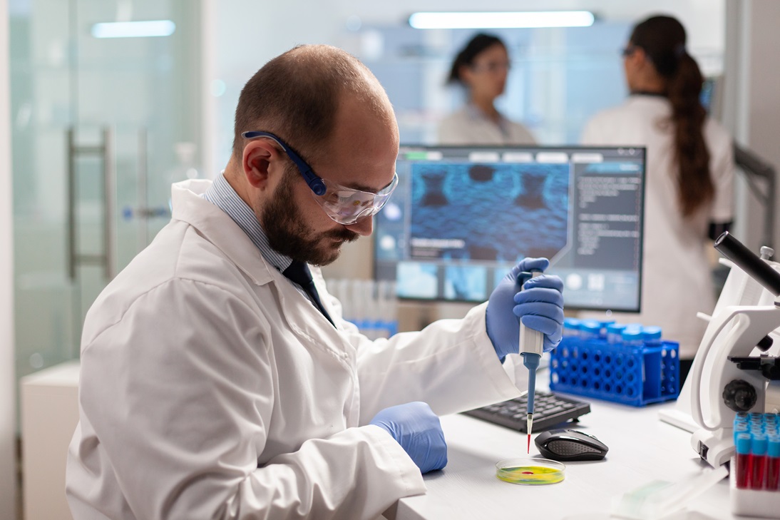 A man in lab coat and goggles working on something.