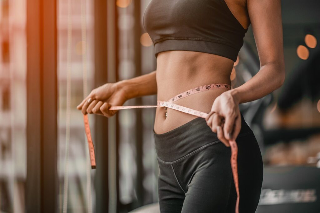 A woman is measuring her waist with tape.