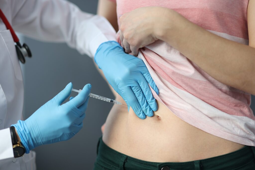 Doctor injecting patient's abdomen.